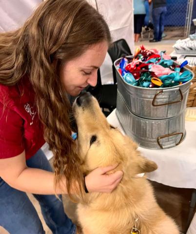 Dr. Brongo petting a golden retriever mix dog at the pet adoption event